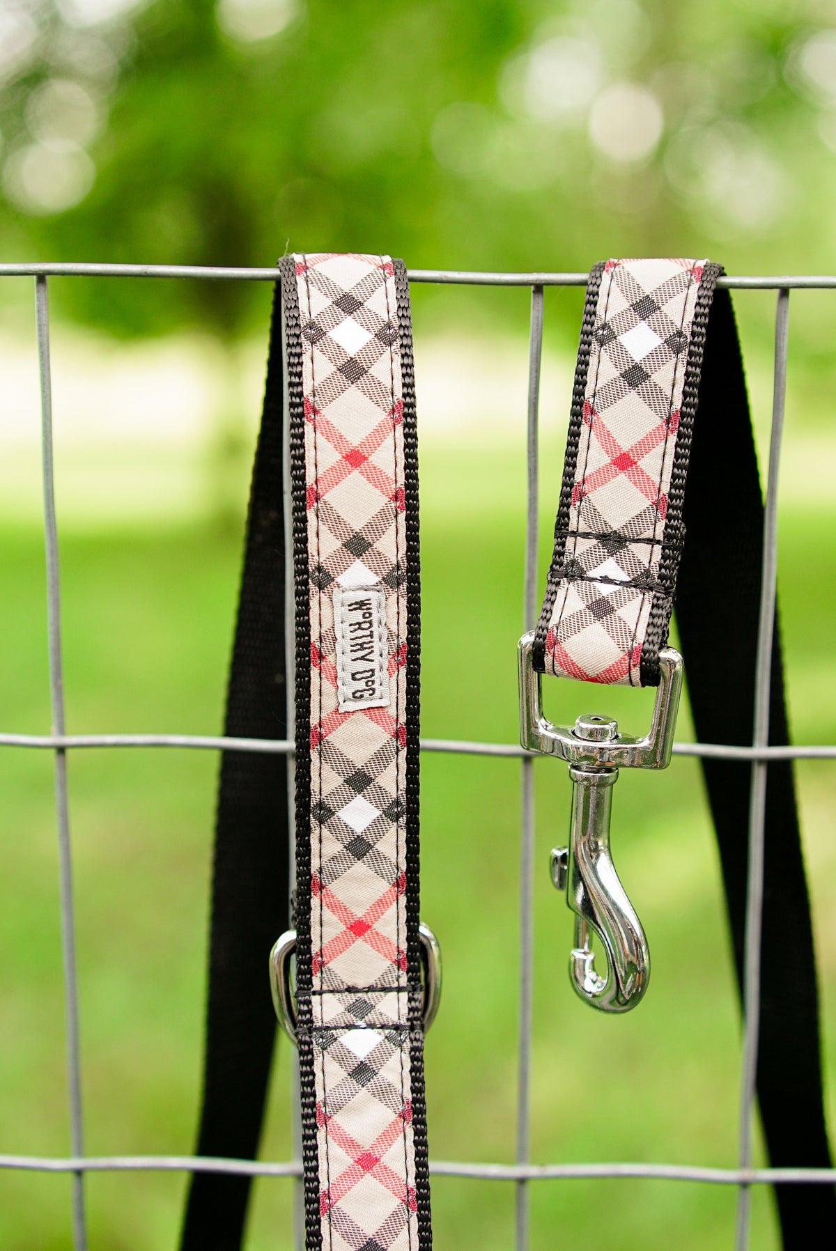 Beige plaid leash and matching collar hanging on a fence; collar not included