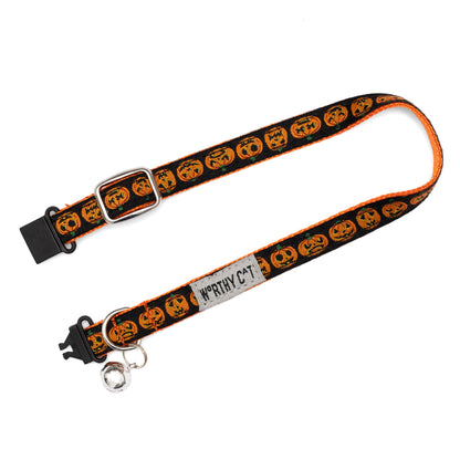 Orange jack-o-lantern faces on black ribbon Halloween cat collar, extended with clasp open